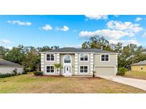 Charming two-story home featuring a well-manicured lawn, attached garage, and inviting front entry with white door at 1617 Myrtle Lake Ave, Fruitland Park, FL 34731