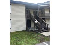 Condo exterior featuring private entrances with stairs and a well-lit walkway, inviting curb appeal at 17202 Sandalwood Dr # 202, Wildwood, FL 34785