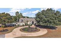 Stately home featuring a circular driveway, lush landscaping, and mature trees offering shade and curb appeal at 1825 Myrtle Lake Ave, Fruitland Park, FL 34731