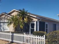 Tan house with white picket fence and palm tree in front at 2067 Broyhill Ave, The Villages, FL 32162