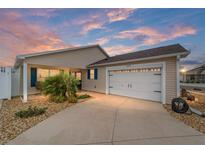 Tan house with white garage door, landscaping, and a walkway at 2222 Southwood Dr, The Villages, FL 32162