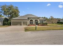 Charming home featuring a three-car garage, arched windows, and a neatly landscaped front yard at 225 Sutherland Ct, Apopka, FL 32712