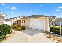 Charming home exterior featuring a one car garage, neutral paint, well-manicured landscaping, and a concrete drive at 2303 Nehaul Ter, The Villages, FL 32162