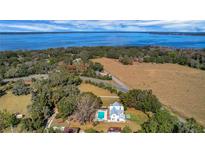 Expansive lakefront property with lush landscaping, pool, and a charming two-story farmhouse at 9210 County Road 48, Yalaha, FL 34797