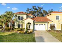 Charming two-story home with a red tile roof, lush landscaping, and a well-manicured lawn at 1055 Avenida Sonoma, The Villages, FL 32159