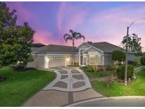 Charming home with a well-manicured lawn, decorative driveway, and a two-car garage under a colorful sky at 11735 Se 173Rd Lane Rd., Summerfield, FL 34491