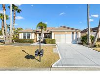 Charming single-story home featuring a well-manicured lawn, complemented by palm trees and an attached two-car garage at 12455 Se 92Nd Ter, Summerfield, FL 34491