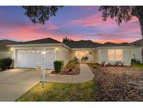 Inviting exterior featuring a two-car garage and well-manicured landscaping at 17145 Se 93Rd Yondel Cir, The Villages, FL 32162