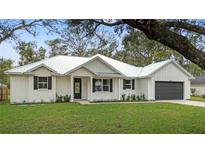 White farmhouse exterior boasts metal roof, shutters, and landscaping at 18315 Dells Cv, Groveland, FL 34736