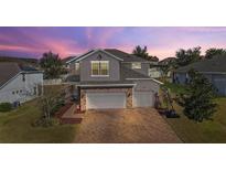 Beautiful two-story home with brick accents, three-car garage, and well-maintained brick paver driveway at 2455 Hastings Blvd, Clermont, FL 34711