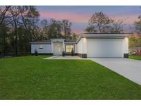 Charming single-story home featuring a manicured lawn and a two-car garage at 8264 Sw 128Th Ter, Dunnellon, FL 34432