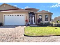 Charming home featuring a well-manicured lawn, brick driveway, and inviting front entrance at 10177 Mainsail Dr, Oxford, FL 34484
