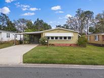 Charming one-story home with well-maintained lawn and mature trees under a sunny, blue sky at 1417 E Schwartz Blvd, The Villages, FL 32159