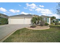 Charming single-story home with a well-manicured lawn, a two-car garage, and attractive landscaping at 1607 Quaker Ct, The Villages, FL 32163