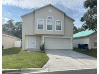 Two-story home featuring a two-car garage, a well-kept lawn, and a classic facade at 2320 Whispering Trails Pl, Winter Haven, FL 33884