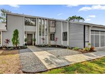 Modern two-story home with gray siding, manicured landscaping, and a welcoming walkway to the front door at 3901 Woodglade Cv, Winter Park, FL 32792