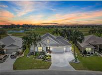 Beautiful single-story home with lush landscaping and golf course views at sunset at 1044 Alcove Loop, The Villages, FL 32162