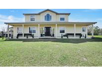 Charming two-story home with a covered front porch, green lawn, and tasteful landscaping at 10909 Mattioda Rd, Groveland, FL 34736