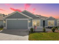 Charming single-story home featuring a two-car garage, well-maintained lawn, and inviting curb appeal at dusk at 1392 Kenneth St, The Villages, FL 34762