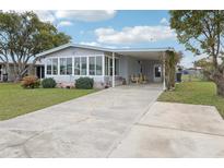 Charming home features an enclosed porch with lots of windows, carport, landscaping and a concrete drive at 1430 Mohawk Cir, Tavares, FL 32778