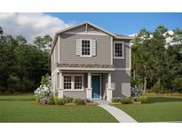 Charming two-story home with gray siding, a blue front door, and a beautifully landscaped front yard at 16812 Hamlin Oasis Loop, Winter Garden, FL 34787