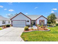 Charming single-story home with a well-manicured lawn, stone accents, and an attached two-car garage at 1914 Antonia Pl, The Villages, FL 32159