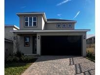 Two-story home with a two-car garage, brick paver driveway, and neutral-colored facade at 2036 Sunshine Peak Dr, Minneola, FL 34715