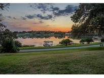 Picturesque lake view with a private boat dock, a charming sunset, and a verdant green lawn at 2422 Topping Pl, Eustis, FL 32726