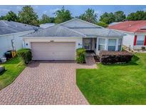 Charming single-story home featuring a two-car garage, brick driveway, and manicured lawn at 32708 Westwood Loop, Leesburg, FL 34748