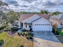 Aerial view of the house showcasing the manicured lawn, driveway, and mature landscaping at 610 Mallory Hill Dr, The Villages, FL 32162