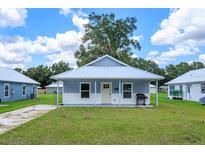 Charming blue cottage home featuring a metal roof, covered porch, and well-maintained front lawn at 654 Nw 9Th Ave, Webster, FL 33597