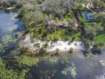 Stunning aerial view of lakefront home featuring a private sandy beach and lush landscaping at 840 2Nd St, Clermont, FL 34711