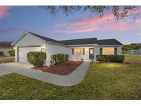 Charming single story home with white siding, tidy landscaping, and an attached garage at dusk at 901 Chula Ct, The Villages, FL 32159