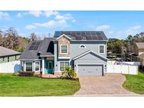 Charming two-story home with stone accents, solar panels, manicured lawn, and welcoming blue front door at 11101 Versailles Blvd, Clermont, FL 34711