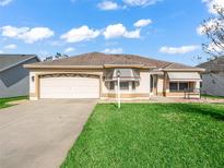 Charming single-story home with a well-manicured lawn, neutral paint, and an attached two-car garage at 1303 Fontana Ct, Lady Lake, FL 32159