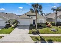 Charming single-story home featuring a manicured lawn, mature palm trees, and a spacious driveway leading to an attached garage at 16726 Hidden Spring Dr, Clermont, FL 34714