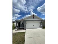 Charming gray single-story home featuring a two-car garage and well-maintained lawn at 1799 Post Oak Dr, Davenport, FL 33837