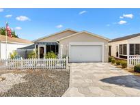 Charming single-story home features a well-manicured lawn, white picket fence, and attached garage at 2495 Birch Ave, The Villages, FL 32162