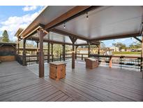 Large wooden deck features a covered seating area and views of the surrounding water and neighborhood at 26608 E Cove Dr, Tavares, FL 32778