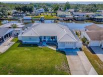 Waterfront single-story home with a metal roof, green lawn and a boat dock and lift on a canal at 26608 E Cove Dr, Tavares, FL 32778