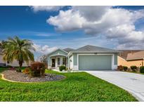 Charming single-story home featuring manicured lawn, rock garden, and attached two-car garage at 27004 Nature View St, Leesburg, FL 34748