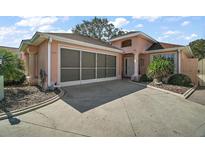 Charming single Gathering home featuring a screened in garage, concrete driveway, and meticulously manicured landscaping at 932 Medira Dr, The Villages, FL 32159