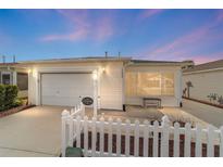 Charming home featuring a one-car garage, white picket fence, and inviting, enclosed front porch at 17454 Se 81St Newberry Ct, The Villages, FL 32162