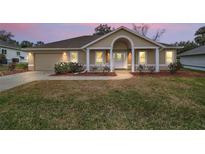 Charming single-story home featuring a well-manicured lawn and inviting entrance with white columns at 11053 Se 174Th Loop, Summerfield, FL 34491