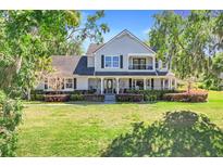 Inviting two-story home featuring a covered front porch and lush landscaping at 12802 Amber Ave, Clermont, FL 34711