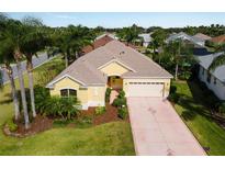 Landscaped yellow home with a two-car garage and palm tree lined street at 1619 Duffy Loop, The Villages, FL 32162