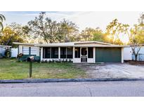 Charming single-story home featuring a well-maintained lawn, mature trees, and a welcoming screened porch area at 2026 Sunset Ln, Clermont, FL 34711