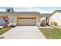 Attached garage with a concrete driveway and manicured lawn provides convenience and curb appeal at 2229 Cypress Ct # C-4, Tavares, FL 32778