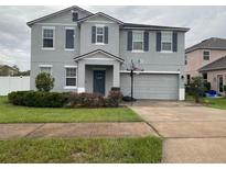 Charming two story home featuring blue exterior, well manicured lawn, and two car garage at 303 Red Kite Dr, Groveland, FL 34736