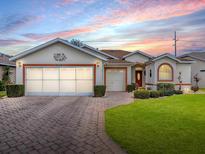 Charming home exterior showcasing a brick driveway, lush lawn, and an attached two-car garage at 33409 Pennbrooke Pkwy, Leesburg, FL 34748